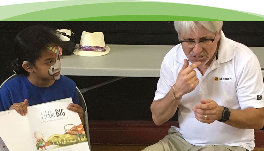  Un hombre mayor trabaja como intérprete de un grupo de niños mientras se lee un libro.
