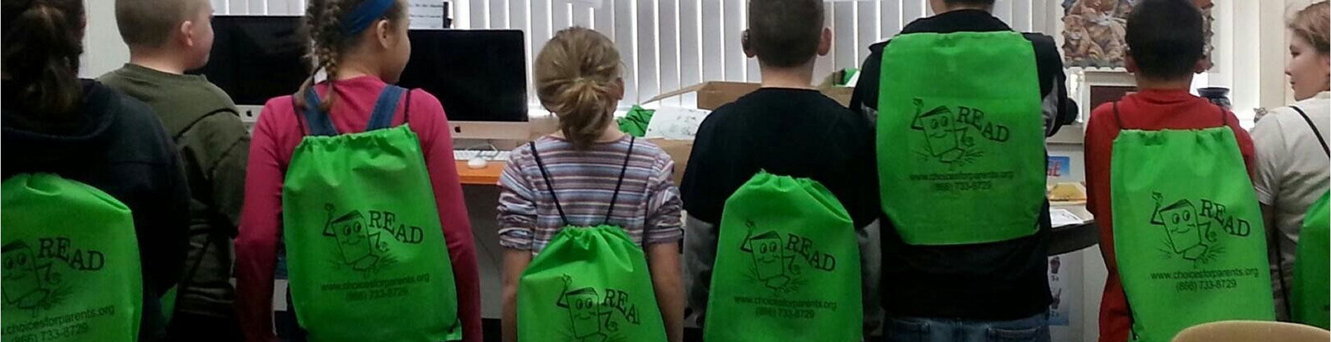 Muchos niños felices usando todos mochilas verdes y viendo a las computadoras en el Programa Escucha la Ovación